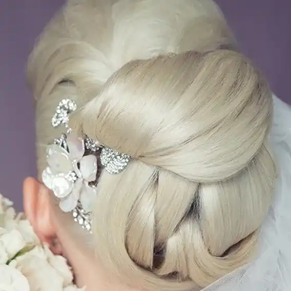 Elegant bridal updo with floral hairpiece and veil.